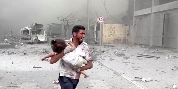 A medic runs as he carries an injured Palestinian child to ambulance in this screengrab taken from a video, in Gaza, October 9, 2023. Photo: Reuters