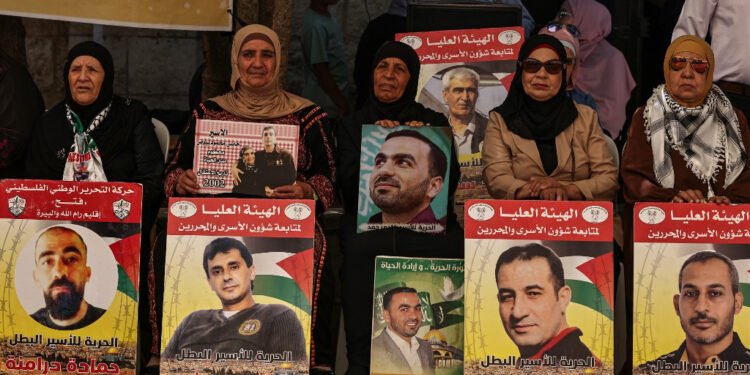 People lift placards bearing portraits of Palestinians currently detained by Israel during a protest in solidarity with them and with the residents of the Gaza Strip, in Ramallah city in the occupied West Bank on July 30, 2024, amid the ongoing conflict in Gaza between Israel and the Palestinian militant Hamas movement. | Photo: AFP